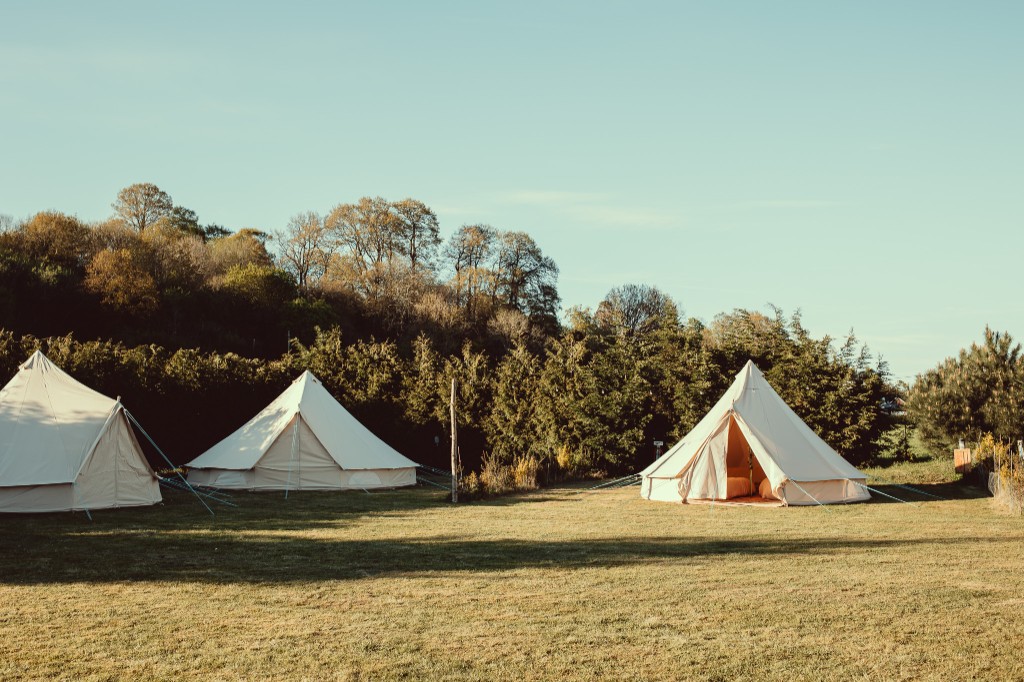 Cream canvas bell tents pitched on grass at golden hour