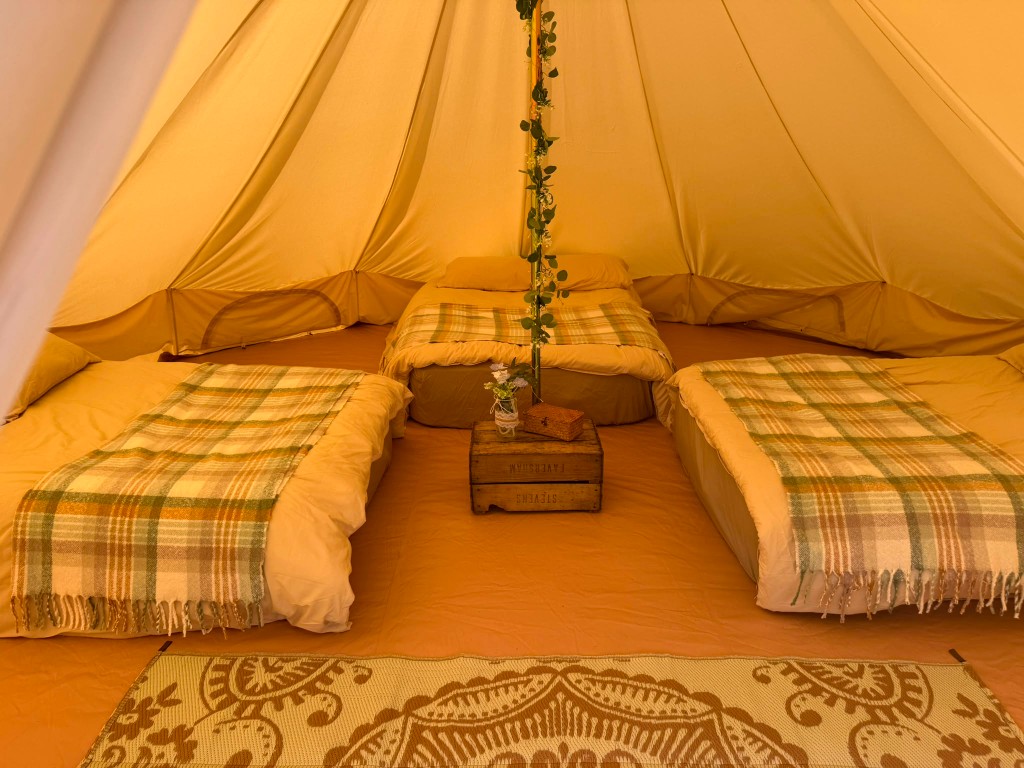 Three-bed Sleep Ready bell tent interior with made-up beds around the centre pole