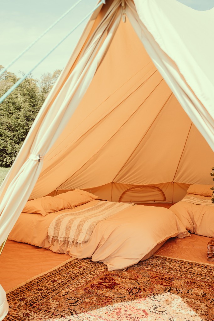 Furnished bell tent interior with peach bedding and a patterned rug
